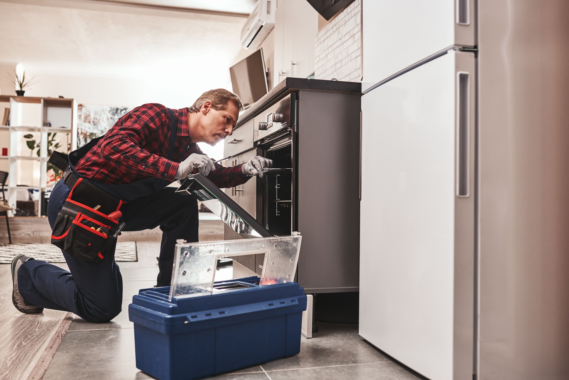 Whats up with oven. Full length of repairman examining oven